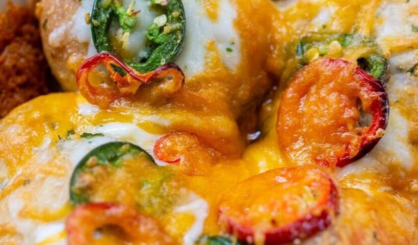 Close-up of a cheesy dish with peppers and herbs
