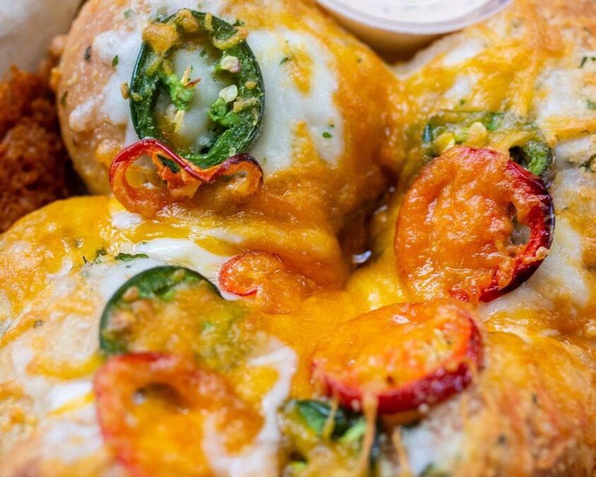 Close-up of a cheesy dish with peppers and herbs